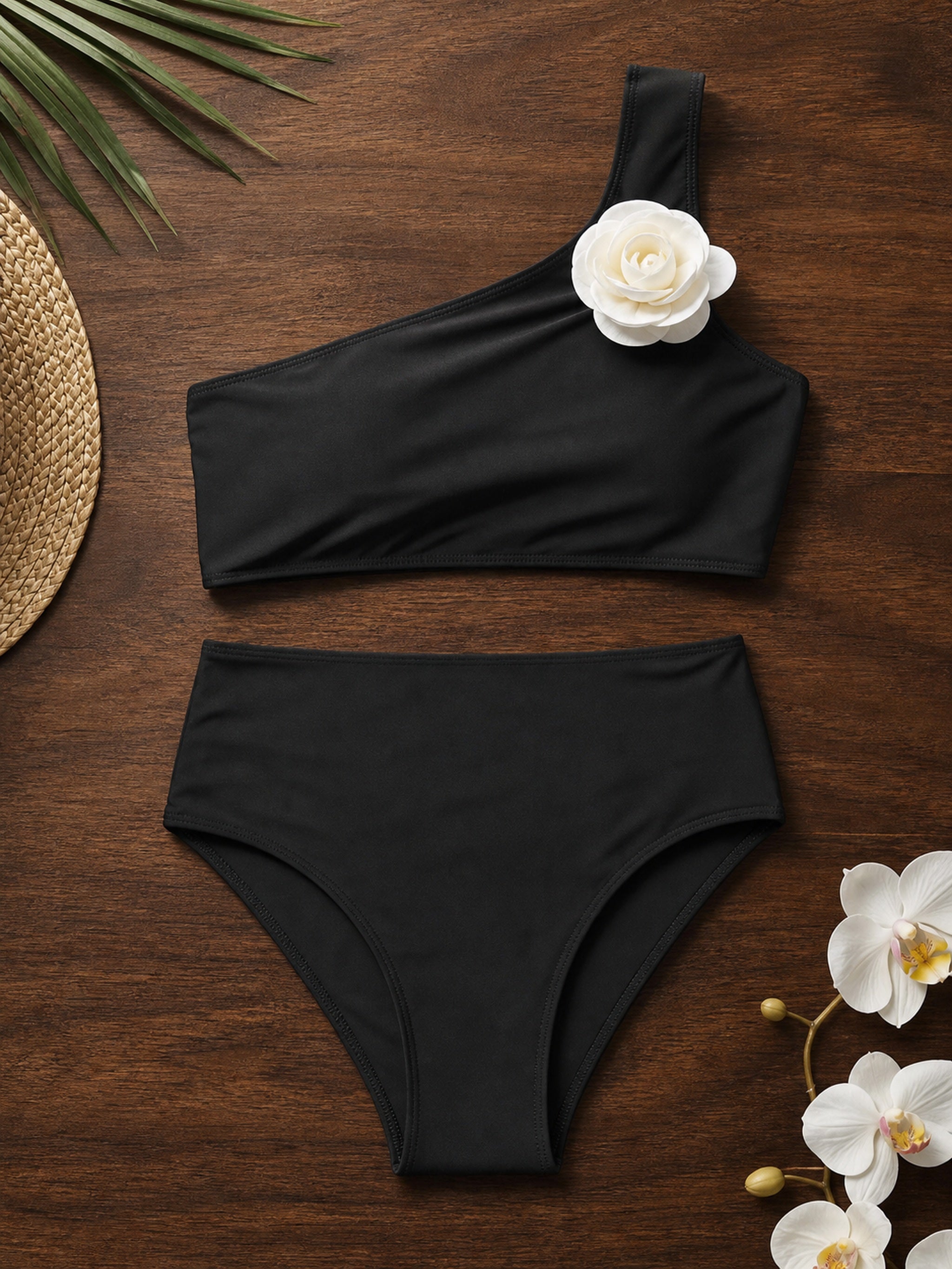 Black cross-strap cutout one-piece swimsuit with draped shoulders on wooden background