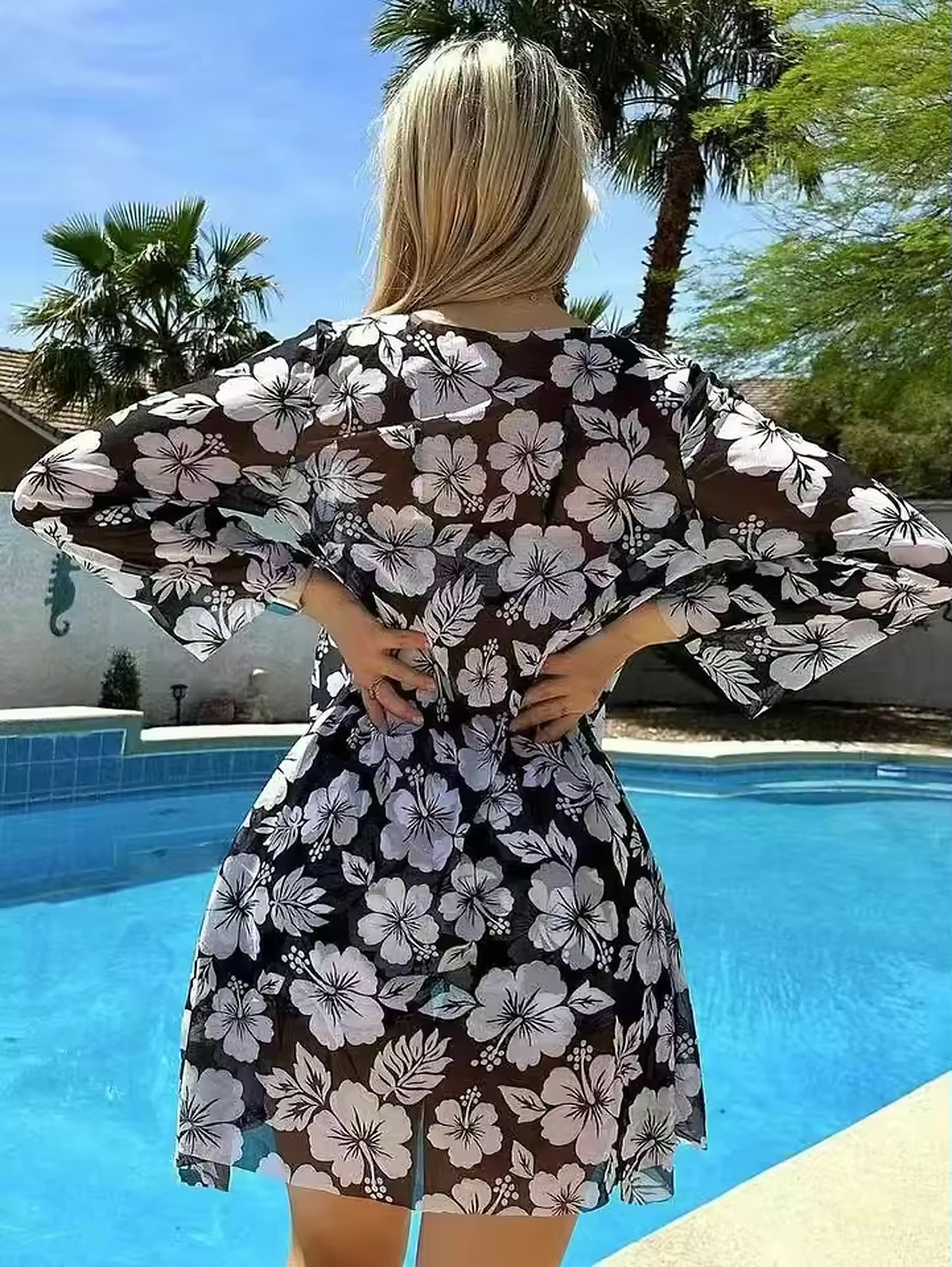 Woman wearing floral black and white Isla Vida bikini with matching cover-up by the pool
