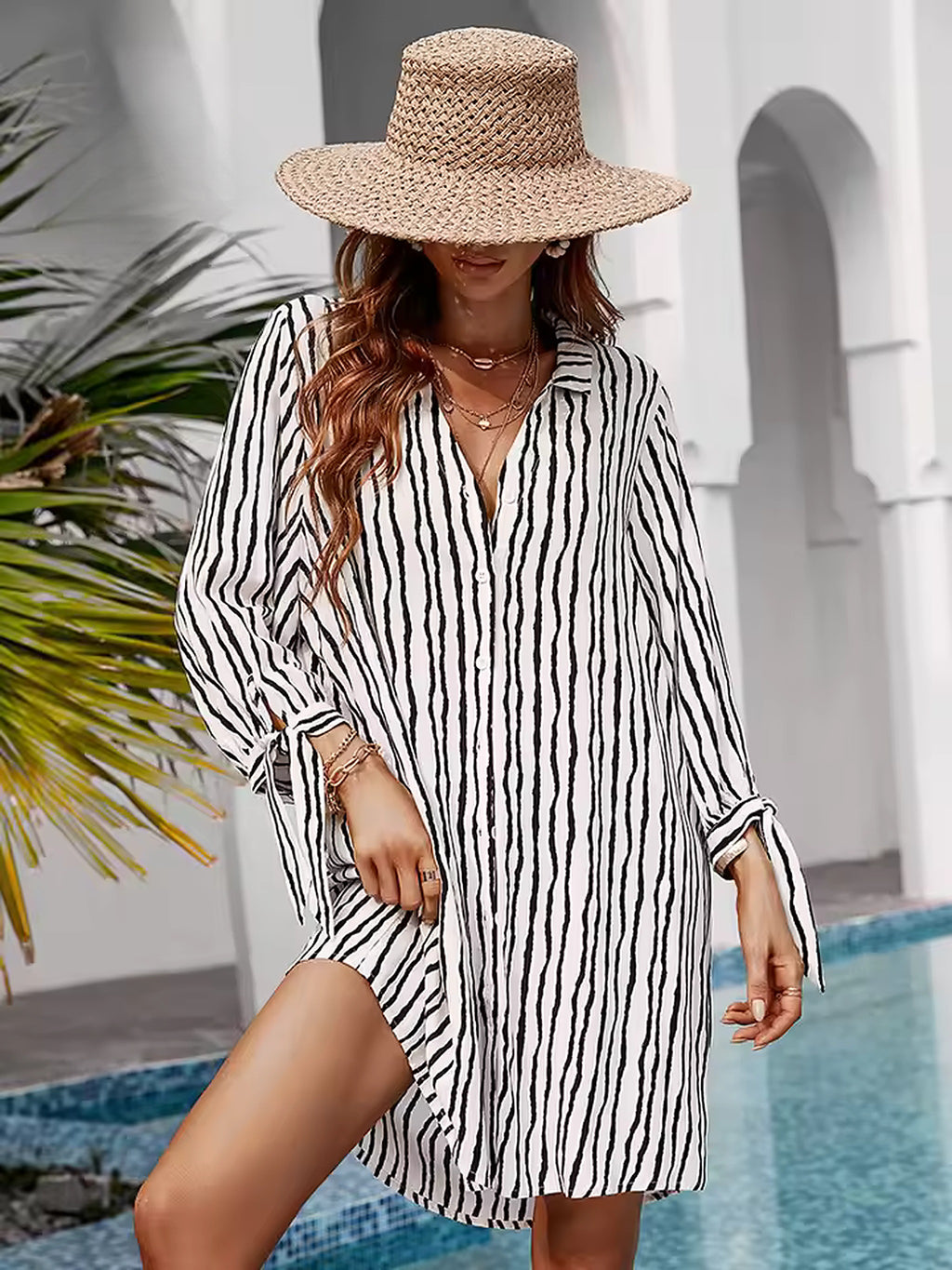 Striped Catch bikini cover-up in black and white vertical stripes, worn with straw hat by pool