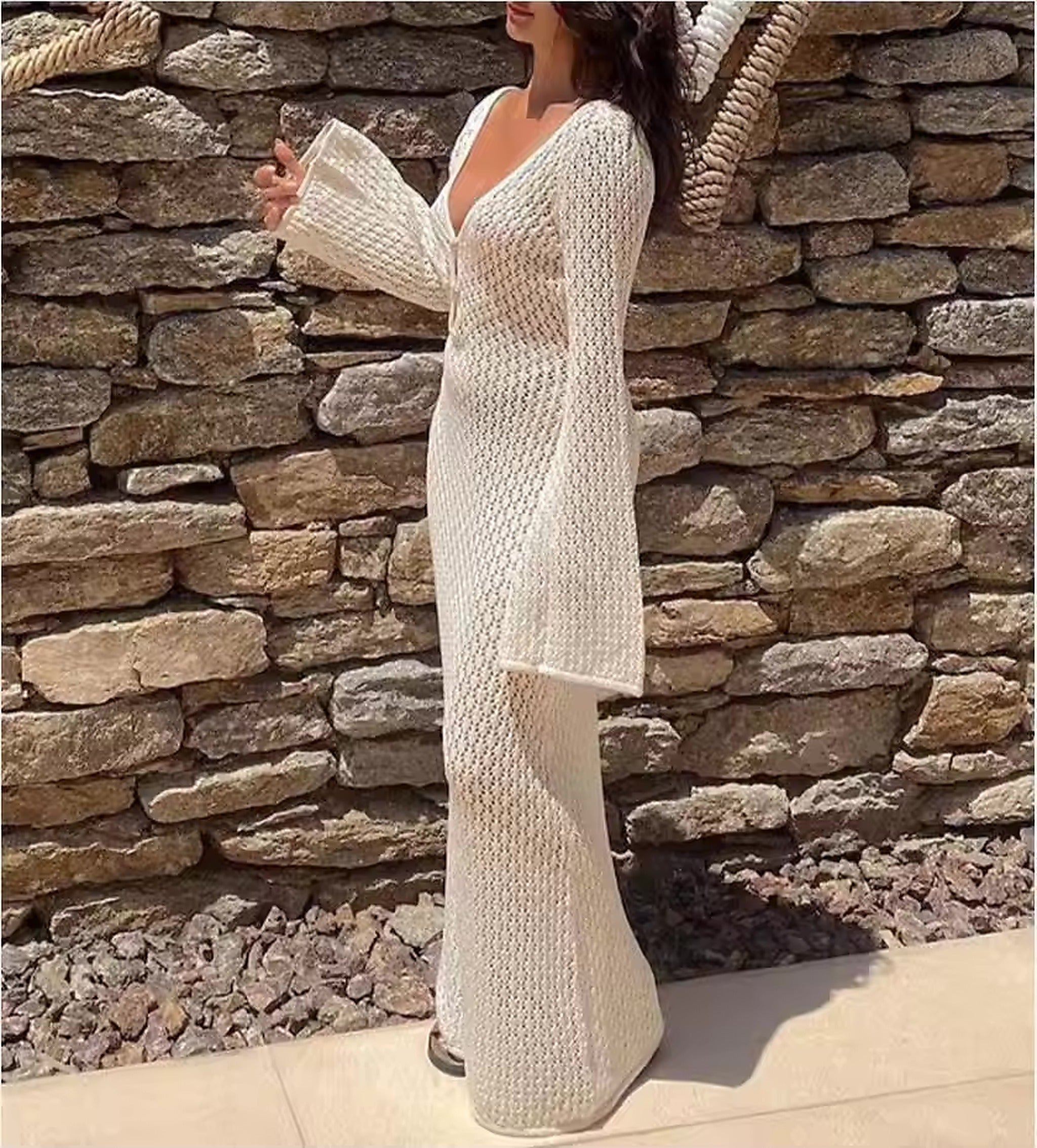 Woman wearing cream knit cover-up over Marbella Muse bikini, standing against stone wall backdrop.