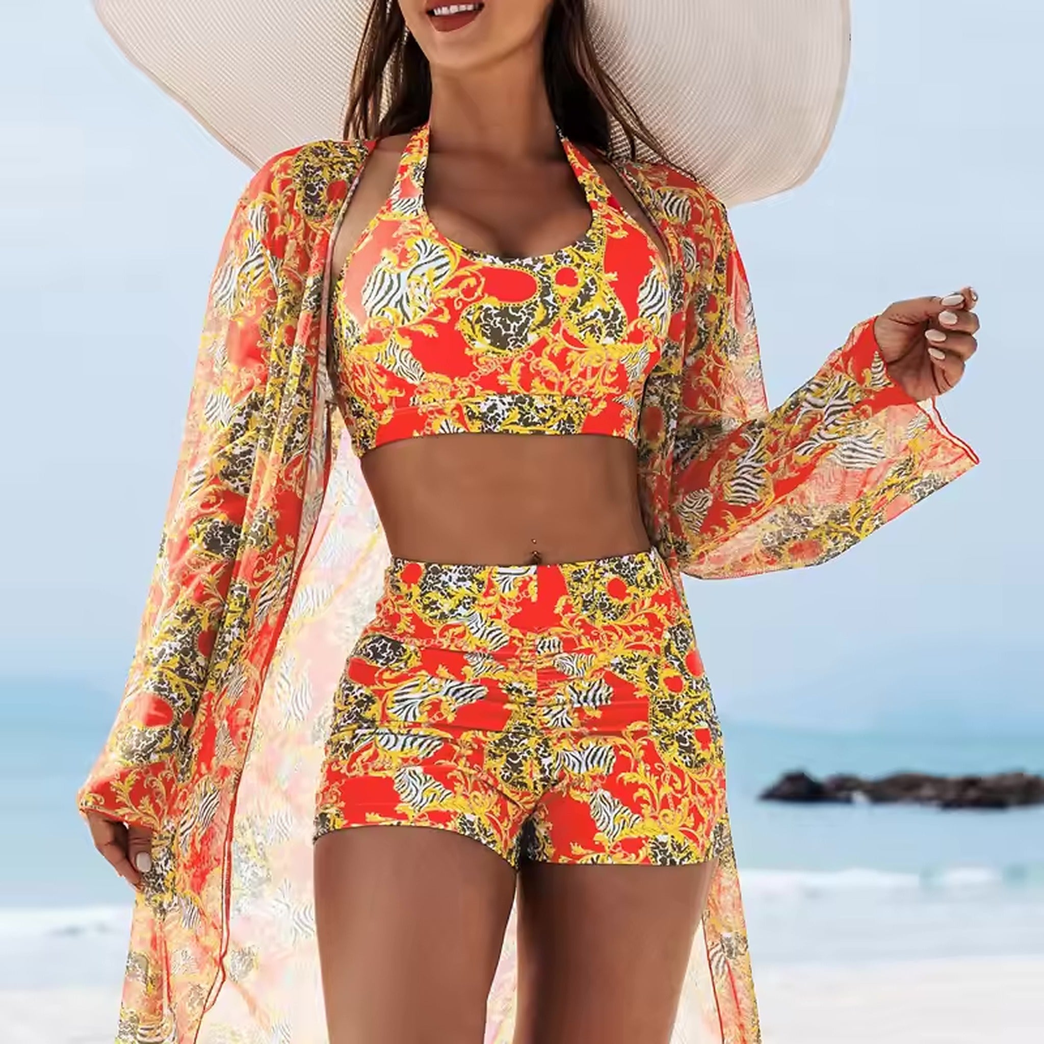 Woman wearing red patterned bikini with matching cover-up and wide-brimmed hat at the beach
