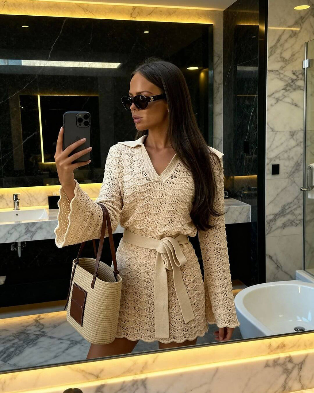 Cream knit wrap dress with V-neckline and tie waist, styled in luxurious bathroom setting.