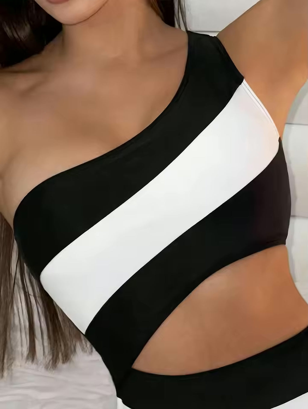 Black and white color-block one-piece swimsuit with diagonal stripe detail and asymmetrical neckline design.