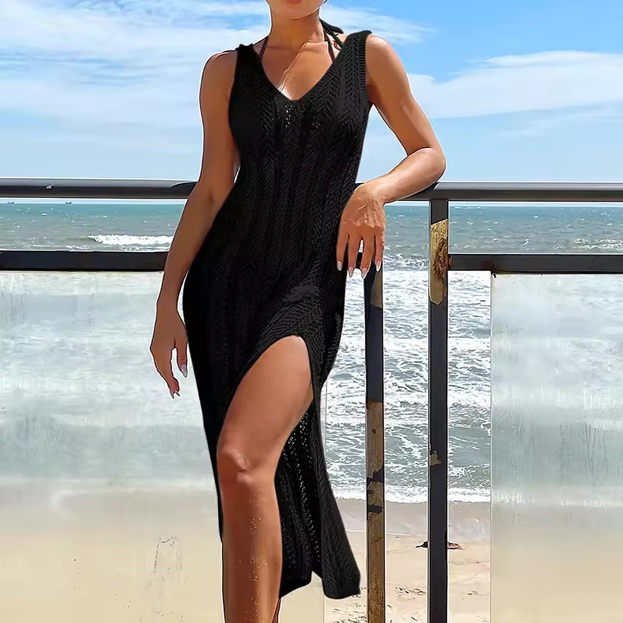 Woman wearing black textured bikini cover-up dress on beach with ocean waves in background