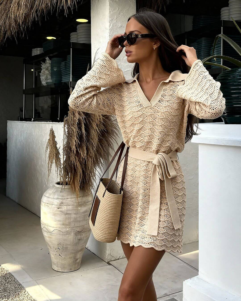 Woman wearing cream knit cover-up dress with belt, styled for resort wear.