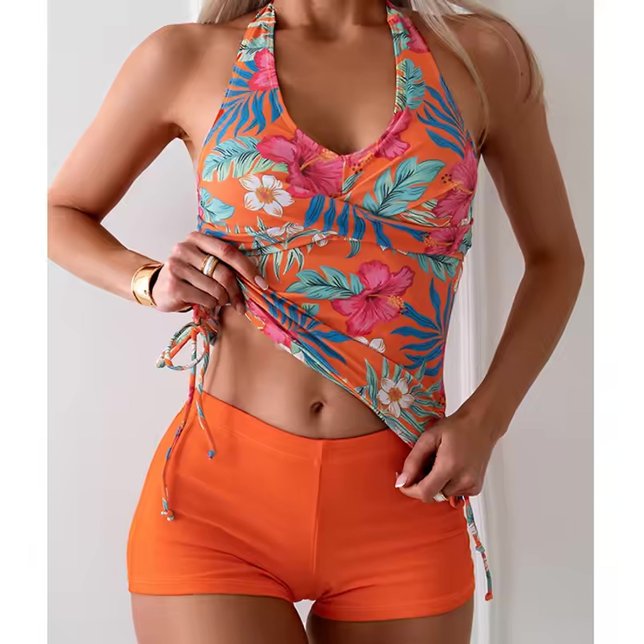 Colorful tropical floral bikini top with vibrant orange base, pink flowers, and blue palm leaves paired with bright orange