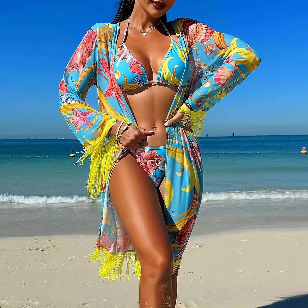 Woman wearing colorful tropical bikini with matching fringed cover-up on sandy beach