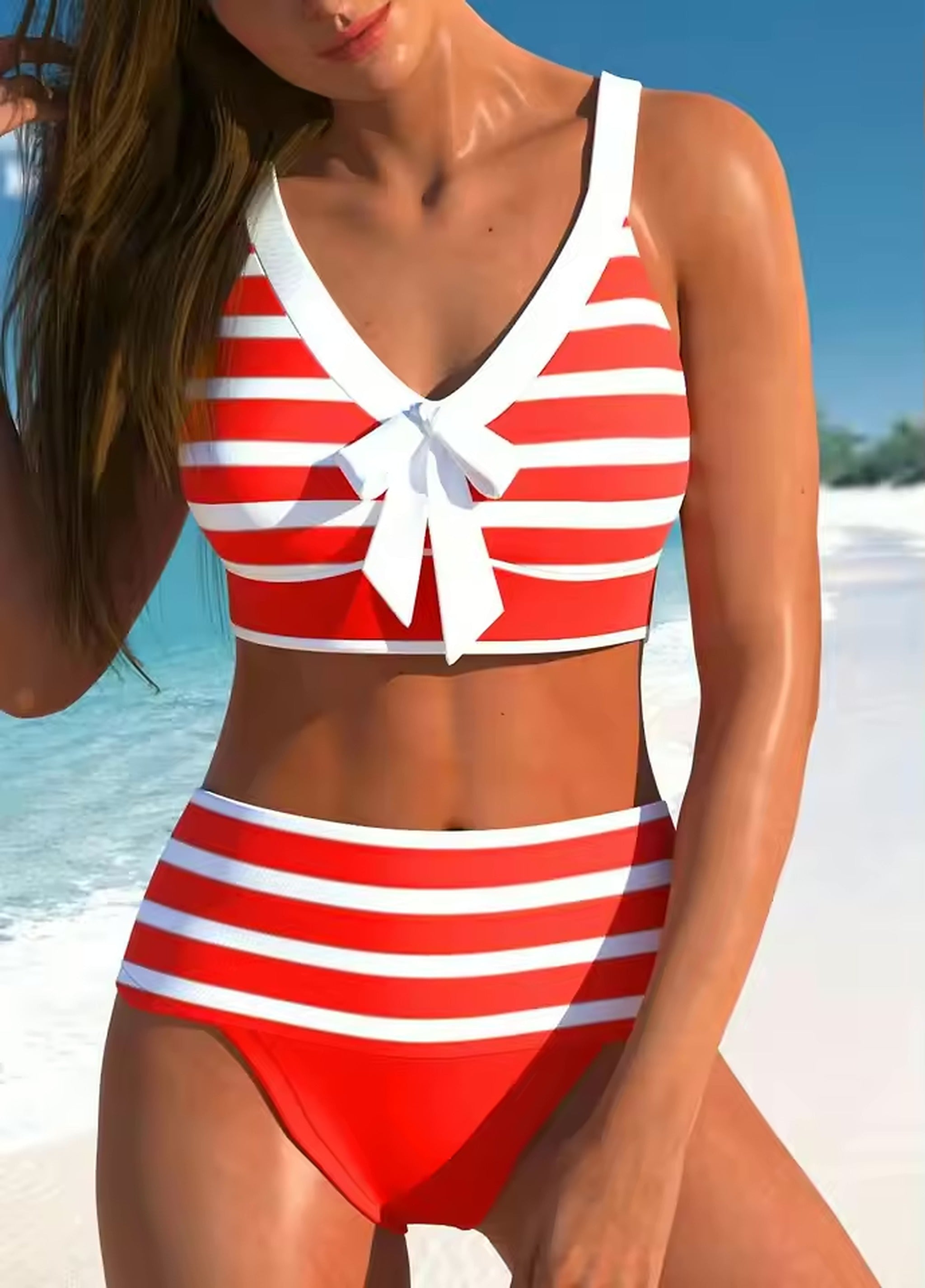 Red and white striped bikini with bow detail, worn on a sunny beach with clear blue water.