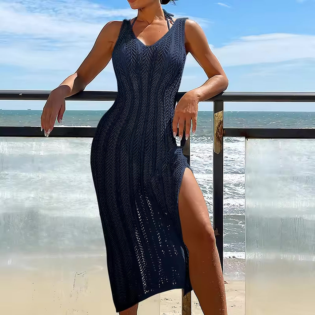 Woman wearing navy Candy Current bikini with knit cover-up dress, standing by beach railing with ocean waves in background.