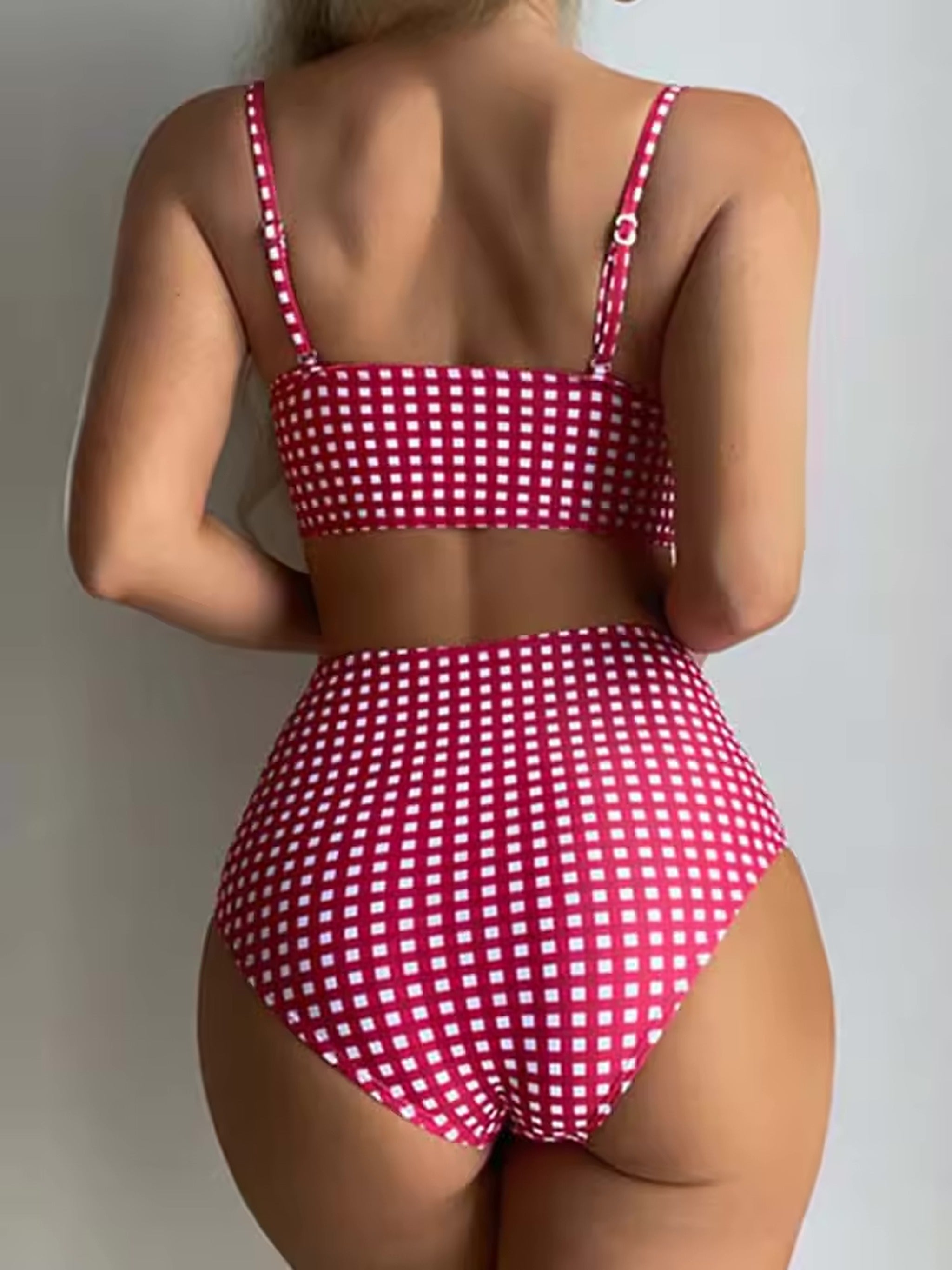 Woman wearing Luna bikini with fuchsia and white gingham pattern, spaghetti straps, and high-waisted bottom, back view.