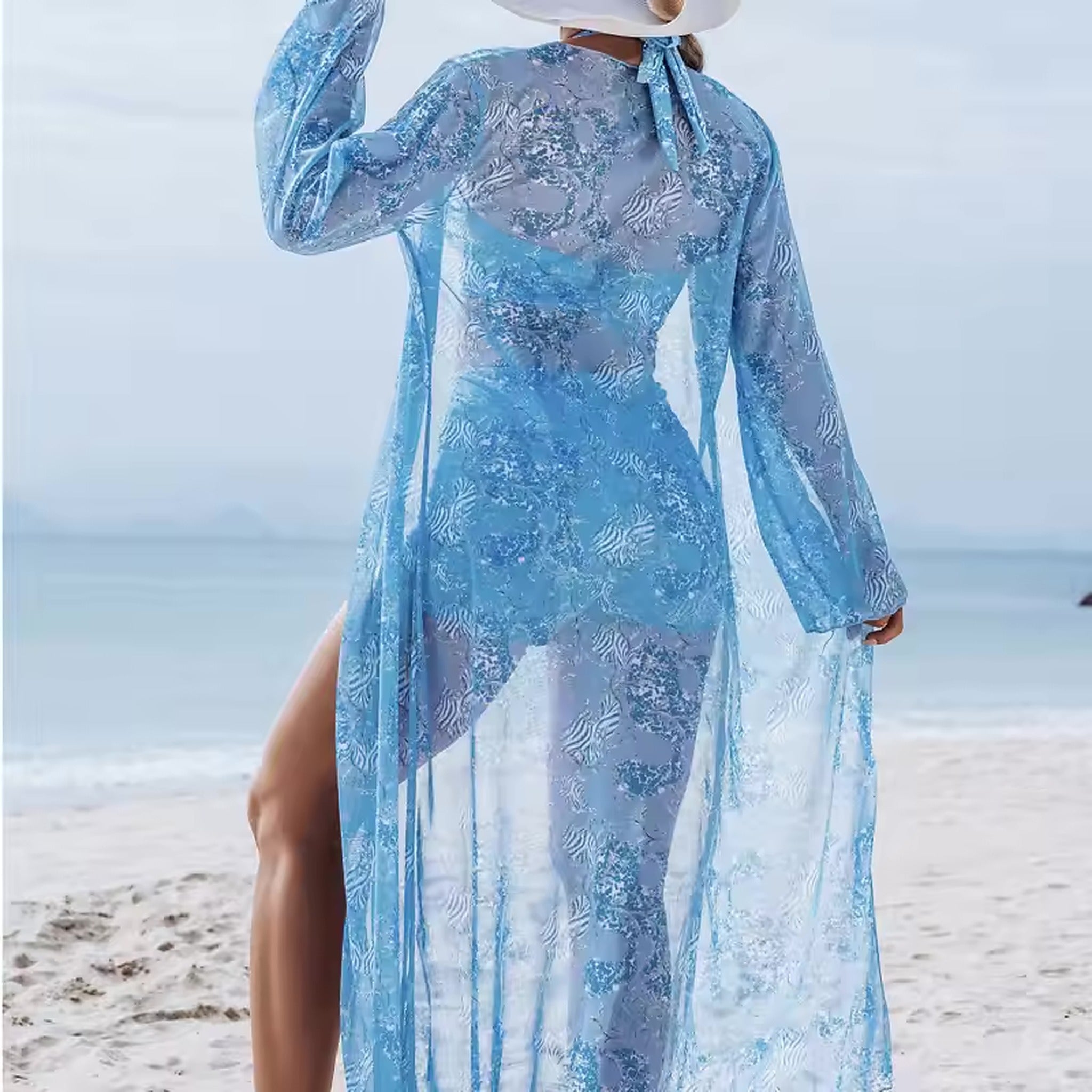 Blue patterned cover-up beach dress with long sleeves worn over bikini at the ocean shore.