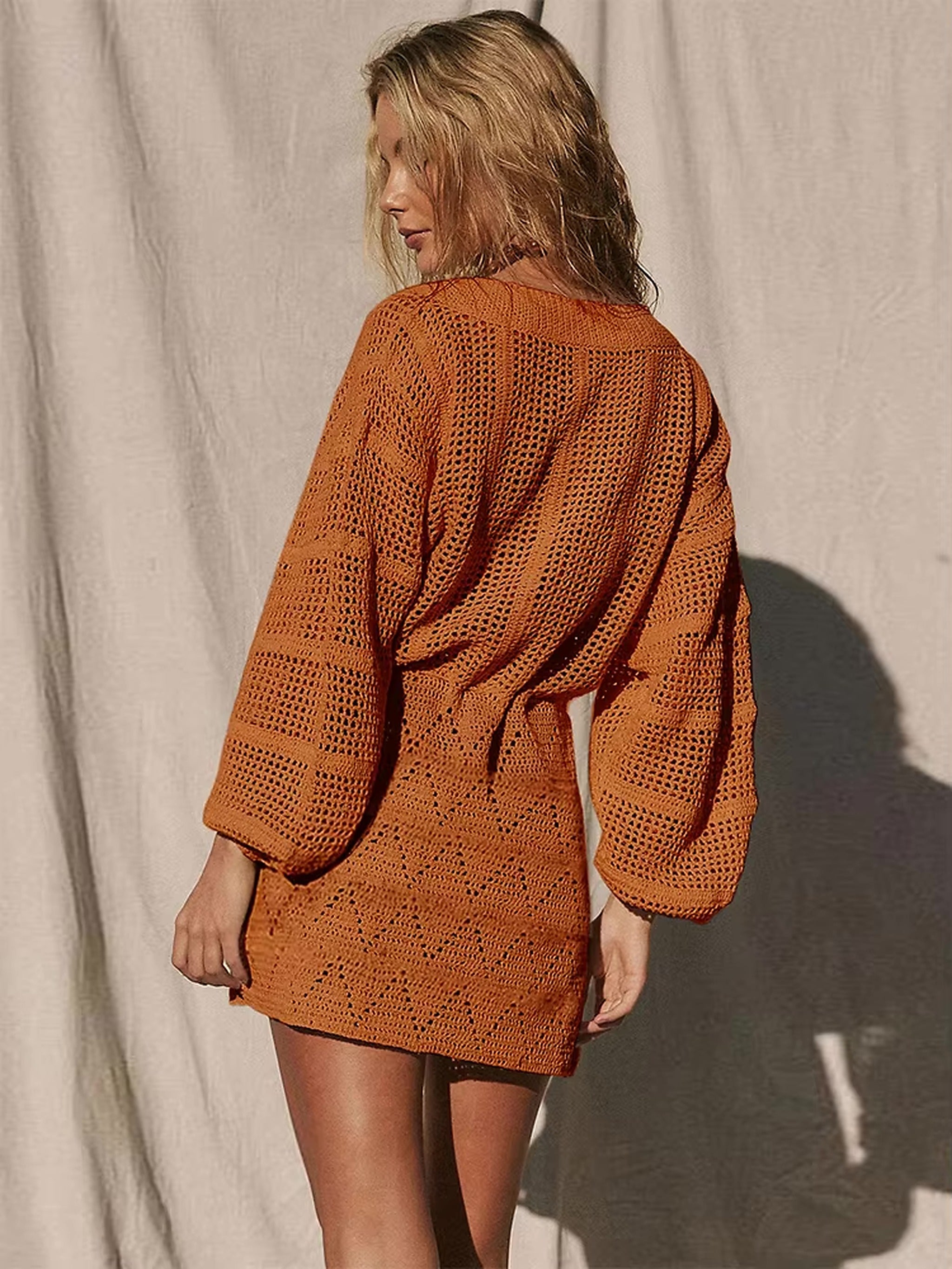Woman wearing burnt orange knit cover-up bikini dress with textured weave pattern and voluminous sleeves.