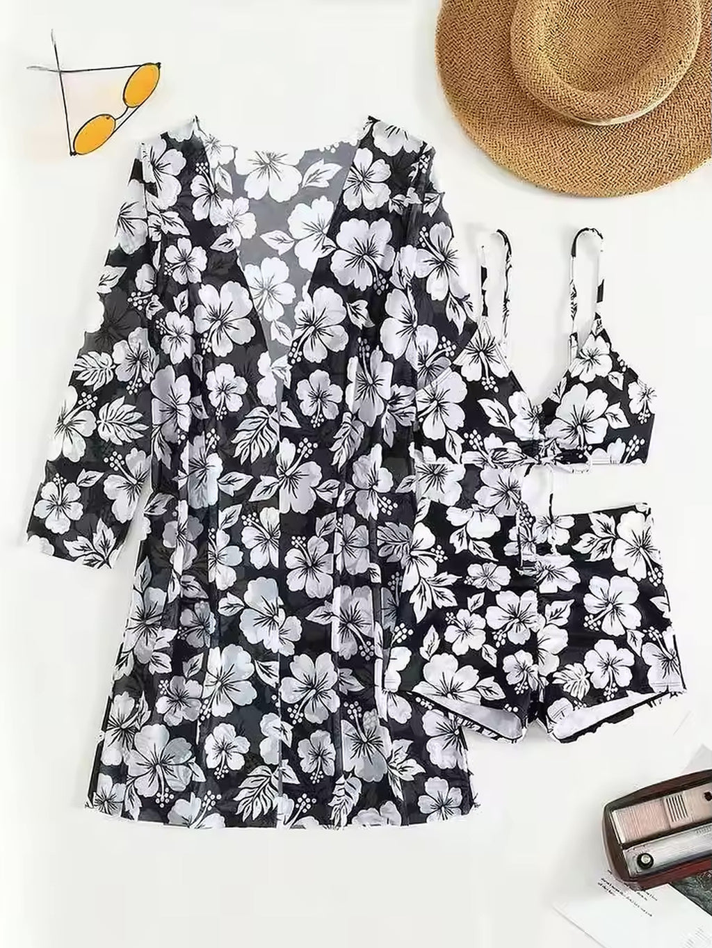 Black and white floral bikini top and shorts set with botanical print, styled with straw hat and sunglasses
